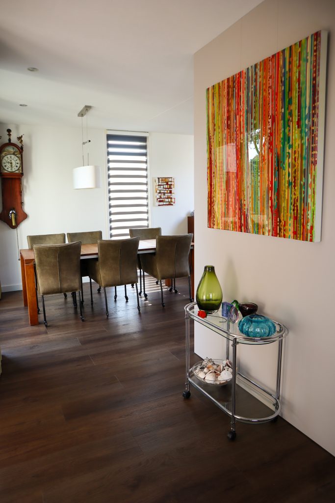 Moderne eetkamer met kleurrijke kunst en klok.