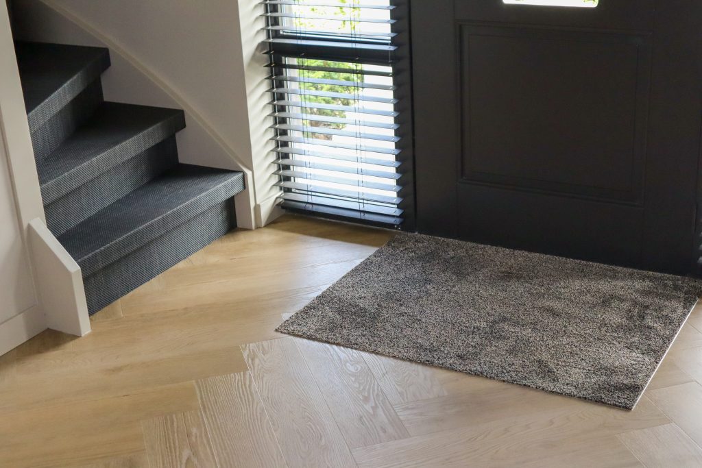 Moderne hal met houten vloer en zwarte deur