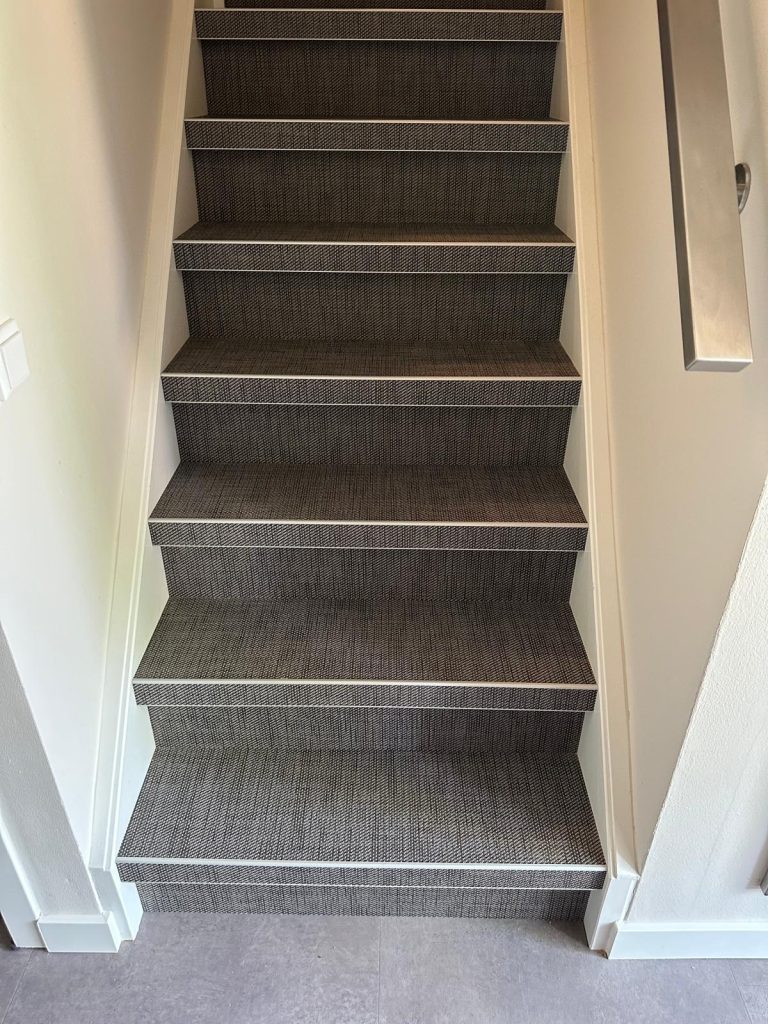Grijs beklede trap met metalen leuning